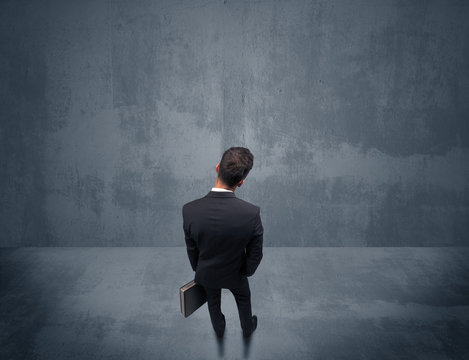 Businessman Standing In Front Of Urban Wall