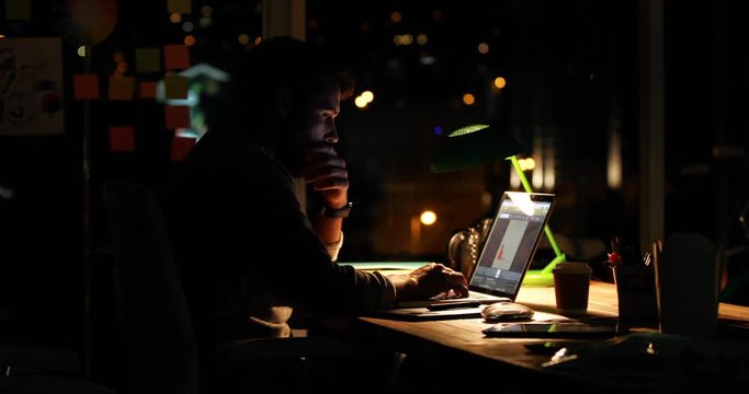 Casual businessman using a laptop at night 