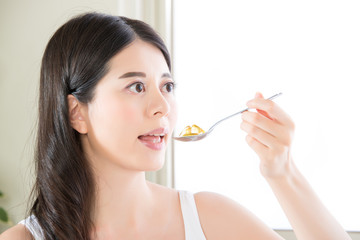 young beautiful asian woman eating nutritional supplement pill f