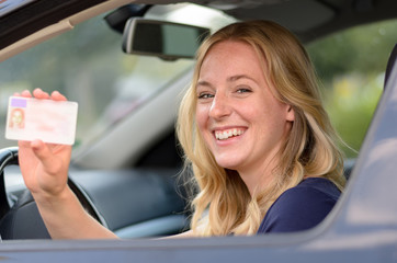 Happy young woman showing off her drivers license