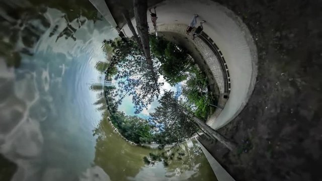 360Vr Video People in the Green Park Embankment of Shallow Pond Limpid Rippling Water Man With Backpack Tourist in Park Trees Reflection Sunny Day Summer 360Vr Video