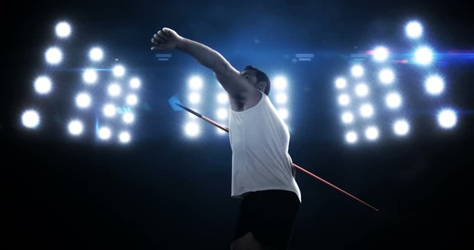Sportsman is practising javelin throw against flashing lights
