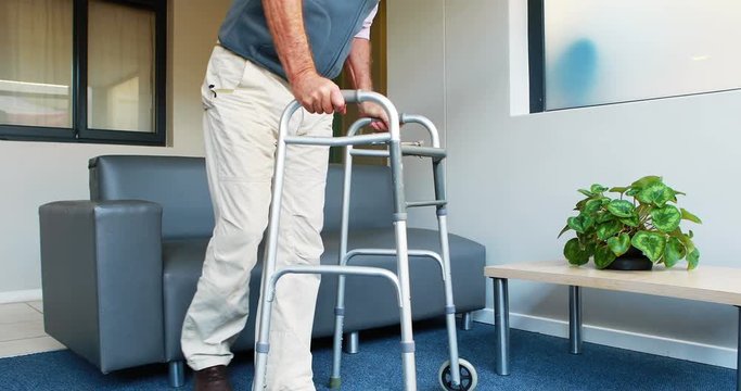 Patient helping himself to have a sit thanks to his zimmer frame in a medical office