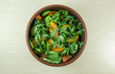 A large portion of salad with fresh basil leaves, arugula, parsley, tomatoes. On a table, top view