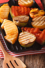 Roasted apple, melon, pear, watermelon and peach on a grill closeup. vertical
