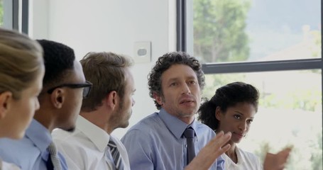 Businesspeople smiling and applauding during a meeting