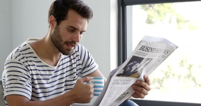 Man is reading newspaper at home 