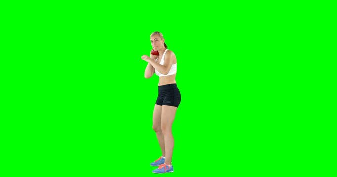 Sportswoman is practising discus throw against a green screen 