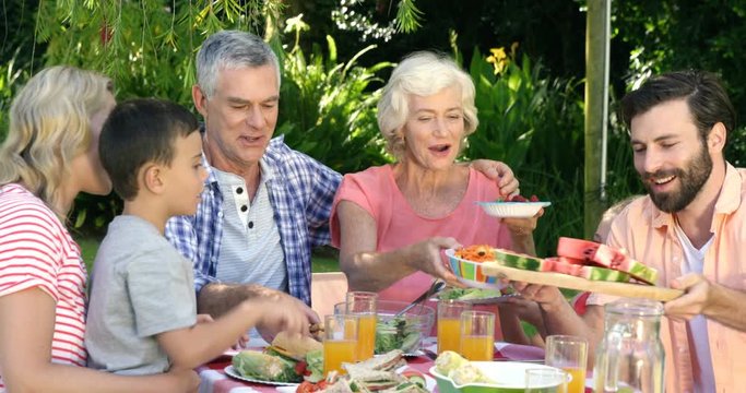 Multi-generation family is eating in the garden on a sunny day 