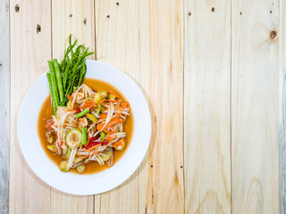 Thai local food style - Spicy papaya salad in white plate on wooden background