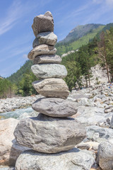 Pyramid from stones on the river bank against a mountain landscape.