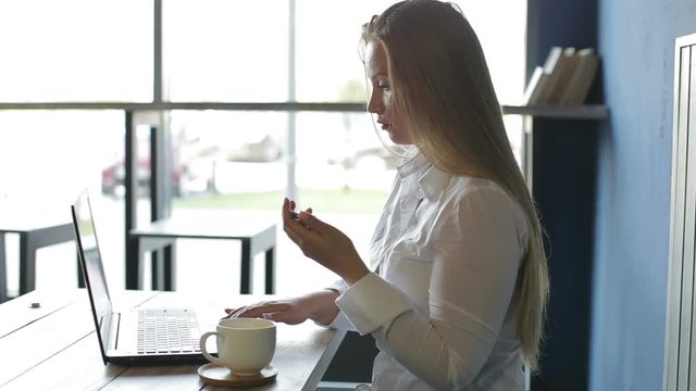 Business woman sitting at a desk using a laptop, drink coffee