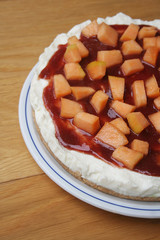 cheesecake al melone e gelatina di fragole su piatto su tavolo di legno