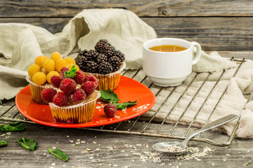 beautiful cupcakes with berries on wooden background in red plate