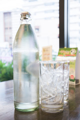 Low key of image of bottle and ice glass near the window in the restaurant background