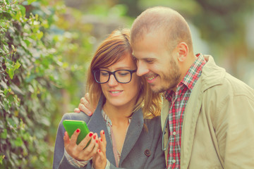 Couple using cellphone outdoors.