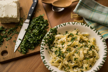 Turkish Noodle / Eriste with cheese and parsley on a wooden surface.