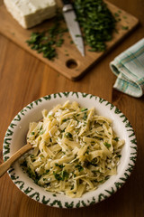 Turkish Noodle / Eriste with cheese and parsley on a wooden surface.