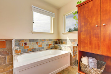 View of bathtub with natural stone tile trim