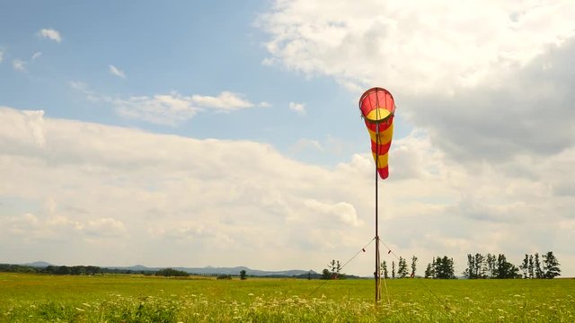 Summer hot day on sport airport with abandoned windsock, wind is blowing and windsock is moving