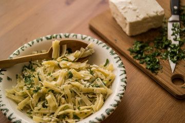Turkish Noodle / Eriste with cheese and parsley on a wooden surface.