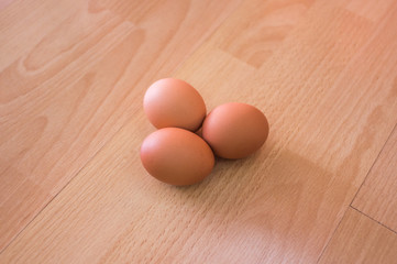 Group of three hen egg on wooden table/ floor background