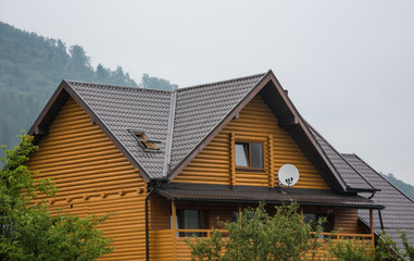 Fototapeta na wymiar Wooden round timber house among trees in mountains
