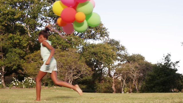 Cute girl is running with balloon in a park 