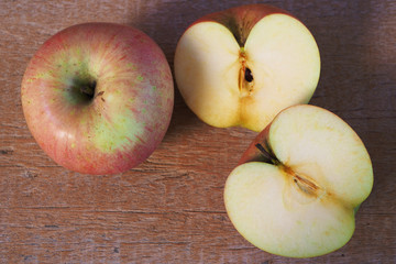 Top view of sliced and whole apple on a wooden background.