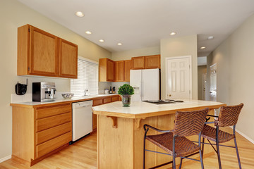 Light wooden kitchen interior with kitchen island and wicker stools