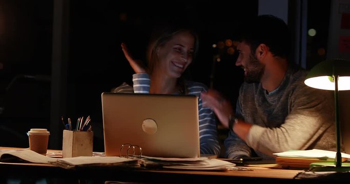 Casual colleagues using a laptop at night