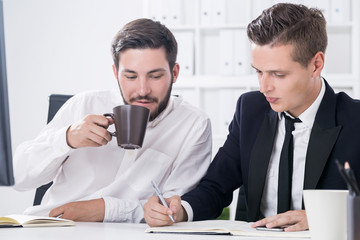 Two colleagues with coffee in office