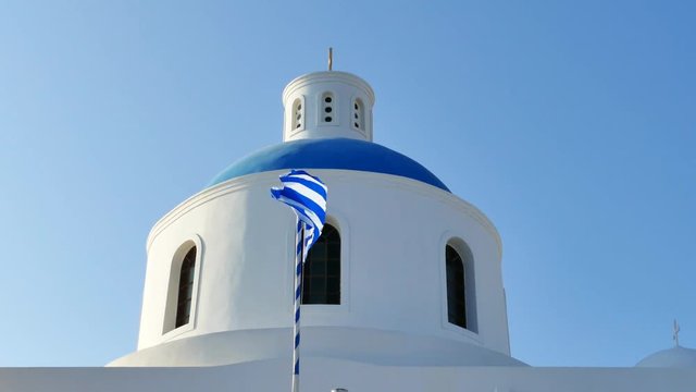 Greek national flag wavin, with a blue church dome in the background