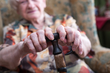 Old woman with her hands on a cane