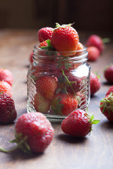 Lots of fresh bright red strawberries and glass jar. Selective f
