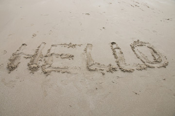 Hello sign word drawing on the sand background.