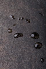 Drops of water on black metal background. The surface of the pan