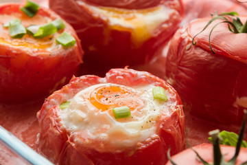 Eggs with rosemary and basil baked in tomato, top view.