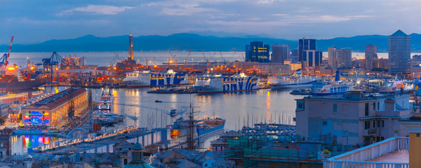 Panorama of Historical Lanterna old Lighthouse, container and passenger terminals in seaport of Genoa on Mediterranean Sea, at night, Italy.