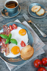 Fried eggs,  bacon, tomato, toast and a cup of coffee