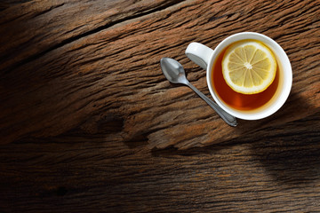 Top view of cup of tea with lemon on wooden table