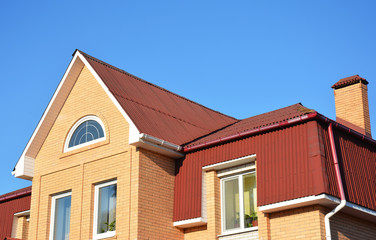 Attic roof exterior with asphalt shingles and plastic rain gutter system