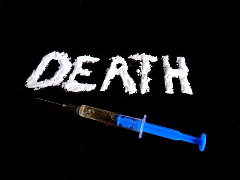 Cocaine drug powder in shaped death word and injection on black background