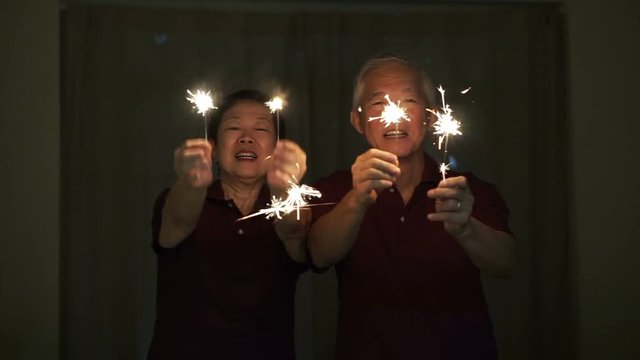 Asian senior couple playing firework, sparklers, fire cracker at night. Concept celebrating life