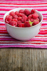 plate with raspberries stands on crocheted striped doily the old wooden table