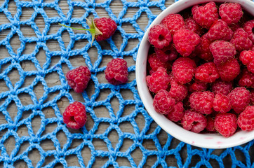 plate with ripe raspberries stands on lace crocheted doily