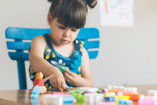 Cut girl playing with play dought in her home.