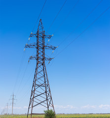 Electricity pylon silhouette against blue sky background. High voltage tower