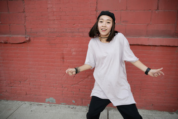 Young Asian woman in city dancing hip hop
