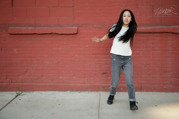 Obraz na płótnie Canvas Young Asian woman in city dancing hip hop